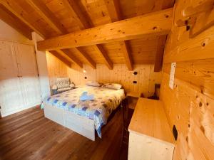 ein Schlafzimmer mit einem Bett in einer Holzhütte in der Unterkunft Rifugio Zoia in Chiesa in Valmalenco