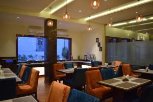 Un restaurante con mesas y sillas y un gran ventanal. en Hotel Ambica Katra, en Katra