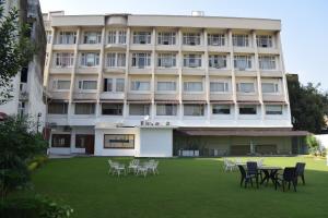 a building with tables and chairs in front of it at Hotel Ambica Katra in Katra