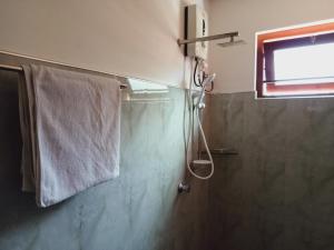 ein Bad mit einer Dusche und einem Handtuch an der Wand in der Unterkunft Deshan Homestay & Restaurant in Tangalle