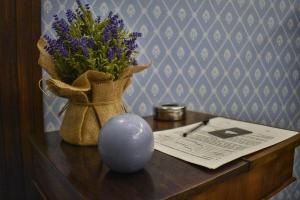 ein Tisch mit einer Vase mit lila Blumen und einem Papier in der Unterkunft Il Confessionale in Castelnuovo di Porto + 29 Fotos