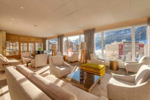 a living room with a couch and chairs and windows at Le Bristol Leukerbad in Leukerbad