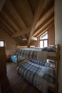 a room with three bunk beds in a log cabin at Rifugio Zoia in Chiesa in Valmalenco