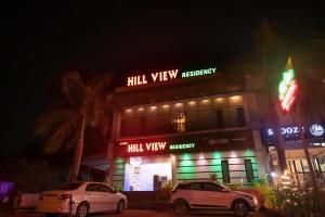 deux voitures garées devant un bâtiment la nuit dans l'établissement VIJAYA HILL VIEW RESIDENCY, à Navi Mumbai