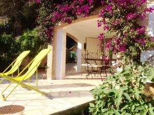 una sedia gialla seduta su un patio con fiori viola di Villa Lou Gecko a Hyères