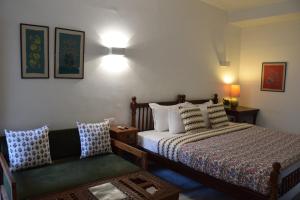 ジャイプールにあるMukam, Boutique Homestayのベッドルーム(ベッド1台、ソファ、ランプ付)