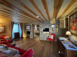 - un salon avec une cheminée en pierre et un mobilier rouge dans l'établissement Il Cuore della Valdigne - Courmayeur-La Thuile- Pré Saint Didier, à Morgex