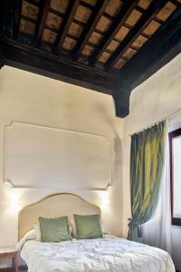 a bedroom with a white bed with green pillows at Palazzo del Magnifico B&B in Siena