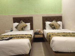 two beds sitting next to each other in a room at Hotel Golden Nest Popular Residency in Mumbai