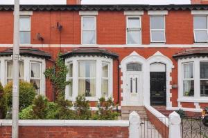 a red brick house with white windows and a porch at Cheerful 4-bedroom holiday home close to the Sea in Blackpool