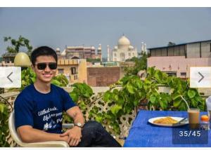 a man sitting at a table with a plate of food at Hotel Sai Palace Walking Distance From Taj Mahal--View of Taj Mahal in Agra