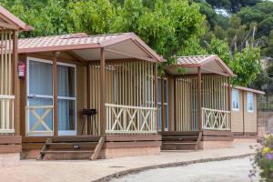 a building with two windows and a wooden fence at Camping Roca Grossa in Calella