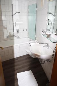 een badkamer met een wastafel, een bad en een spiegel bij Die Krone in Staufen im Breisgau
