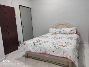 a bed with a white comforter with flowers on it at 55 homestay 4-bedrooms guesthouse in Bukit Bakri Muar Johor in Bakri