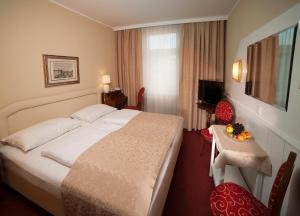 ein Hotelzimmer mit einem großen Bett und einem Tisch in der Unterkunft Hotel Vier Jahreszeiten Salzburg in Salzburg