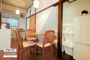 a kitchen with a table and chairs and a refrigerator at GLOCE 葉山 ゲストハウス l 一色海岸のそばでペットと一緒にシーサイドライフ in Hayama