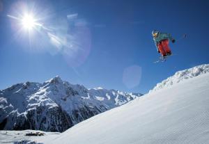een persoon die op ski's in de lucht springt op een met sneeuw bedekte berg bij Apart Bergreich in Längenfeld