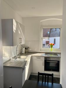 een witte keuken met een wastafel en een raam bij Pension Kaufungen in Kaufungen