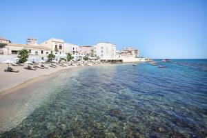 uma vista para uma praia com cadeiras e a água em Musciara Siracusa Resort em Siracusa