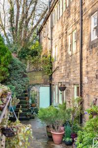 un edificio de ladrillo con una puerta verde y algunas plantas en Cottage Pie - 10mins easy walk to Holmfirth, en Holmfirth