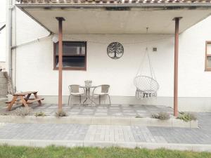 d'une terrasse avec une table, des chaises et une balançoire. dans l'établissement Ferienwohnung Christine mit Sauna und Whirlpool, à Utzerath