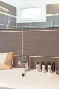 un bagno con lavandino e 5 bottiglie di shampoo su un bancone di SELECT'SO HOME - Résidence La Fossette - Prestations de qualité & Services Hôteliers - FOS-02 a Le Lavandou