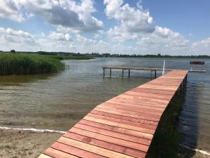 a wooden dock on a river with a bench at Siedlisko Miluki - Apartamenty nad Jeziorem z Jacuzzi & Sauną in Ełk