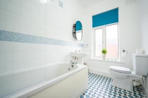 a bathroom with a tub and a toilet and a sink at Brighton House By Horizon Stays in Darlington