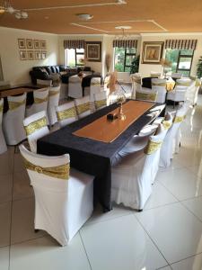 Southgate的住宿－Ecotel Southgate，一间带长桌和白色椅子的用餐室