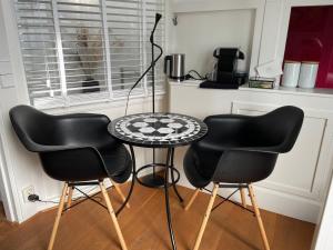 twee zwarte stoelen en een tafel in de keuken bij Prins Heerlijk in Sassenheim