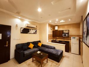 a living room with a black couch and a kitchen at قصر البسمة للشقق المخدومةSMILE Serviced Apartments in Jeddah