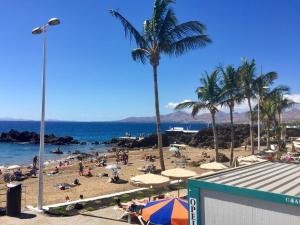 a beach with people and palm trees and the ocean at Marina in Tías