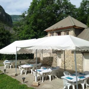 un grupo de mesas y sillas bajo una sombrilla blanca en Le Relais des Cavaliers, en Villeneuve-dʼEntraunes