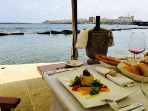 a table with a plate of food and a glass of wine at Musciara Siracusa Resort in Syracuse
