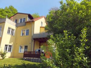 une grande maison jaune avec un balcon et des arbres dans l'établissement FeWo Sonnenblick, à Zinnowitz