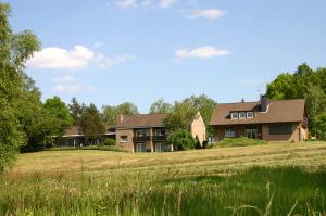 uma casa numa colina com um campo à frente em Pension am Hardausee em Suderburg