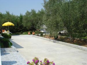 a concrete walkway with a yellow umbrella in a yard at COUNTRY HOUSE IN OLIVE GROVE - Gerakini in Yerakiní