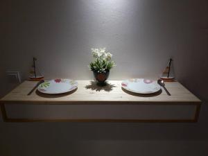 two plates on a table with a vase of flowers at Davidoff Branko Kalezic in Budva