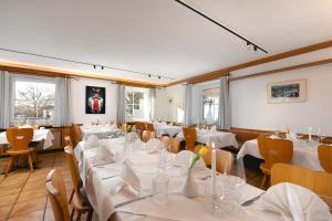 un restaurante con mesas y sillas blancas y ventanas en Zur Blume Hotel & Restaurant Efringen-Kirchen bei Basel, en Efringen-Kirchen