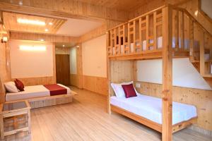 two bunk beds in a room with wooden floors at Khwabeeda Stays in Jibhi