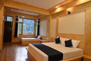 a bedroom with a bed and a large window at Khwabeeda Stays in Jibhi