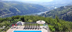 a pool with two umbrellas and a view of a valley at Quinta do Pombal Douro in Penajoia