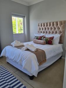 1 cama grande con sábanas blancas y almohadas. en Caribbeans Estates 76/34, en Port Edward