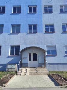 un edificio blu con una porta e scale di fronte di Apartmán Esser 4 a Milovice