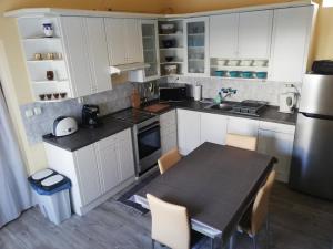 kuchnia z białymi szafkami i stołem z krzesłami w obiekcie Kornél Apartman w Siófoku