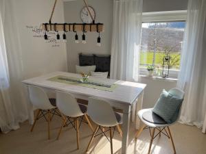 mesa de comedor blanca con sillas blancas y ventana en Ferienhaus Hopfental, en Kelheim