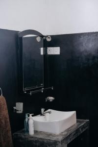 a bathroom with a white sink and a black wall at Karu's place in Hikkaduwa