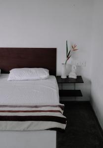 a bedroom with a white bed with a wooden headboard at Karu's place in Hikkaduwa
