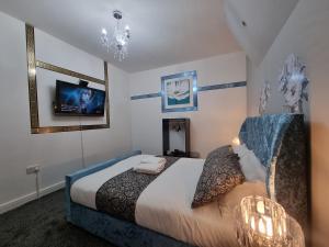 a bedroom with a bed and a tv on the wall at *** Well equipped home for a relaxing cosy and luxurious fun stay + Free Parking + Free Fast WiFi *** in Farnley