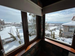 a room with two windows looking out at a snow covered yard at Chalet D'elite in Palaios Agios Athanasios